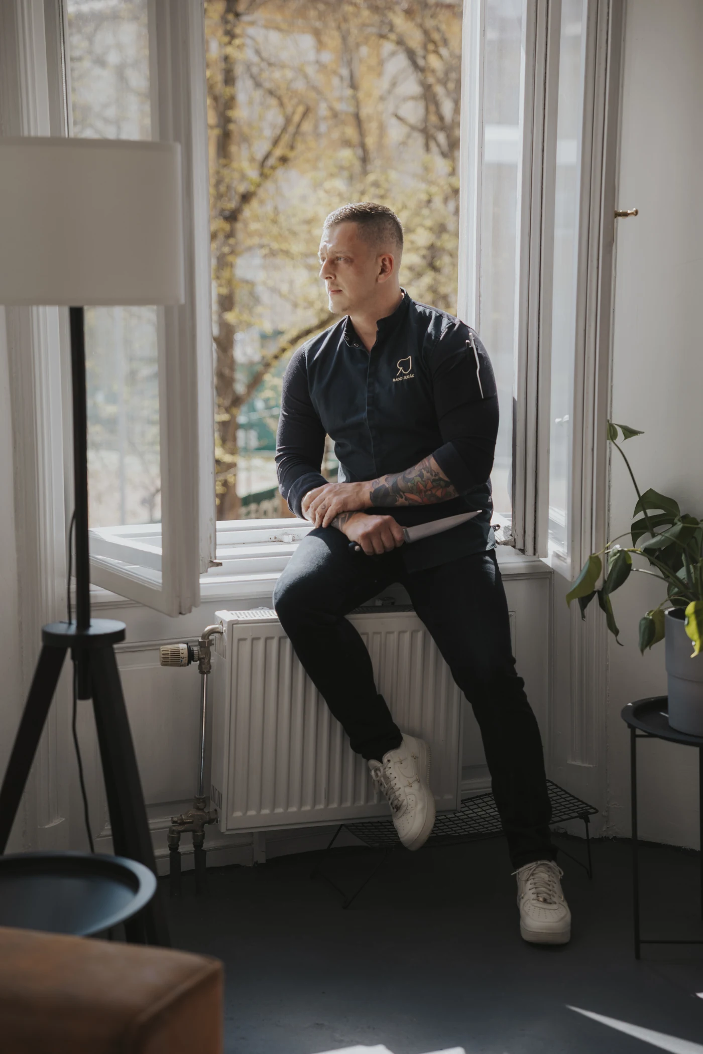 Rado Jurák v čiernej kuchárskej uniforme pri okne